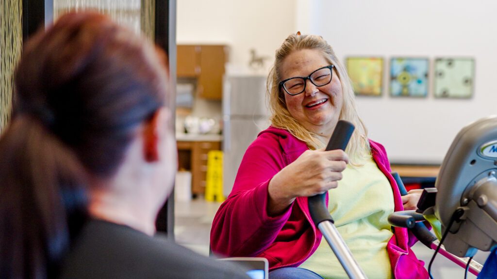 A smiling woman in short term care using therapy equipment for physical therapy